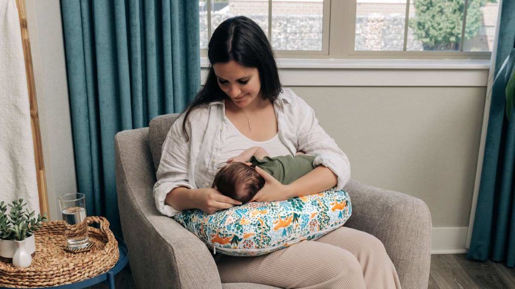Mother using a breastfeeding pillow to support newborn feeding